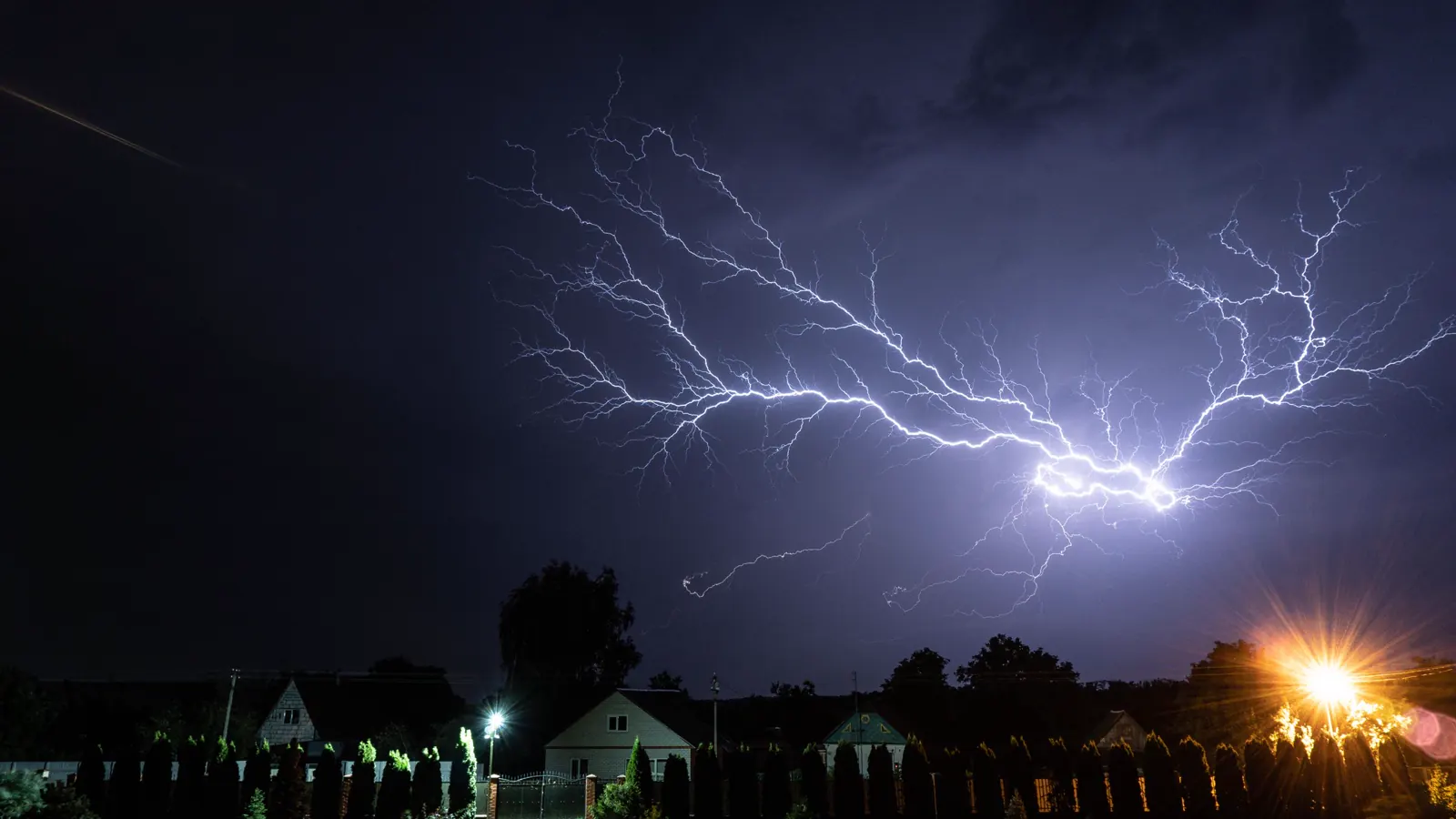 Raio sobre casas à noite, uma das causas de dano elétrico que o seguro residencial pode cobrir